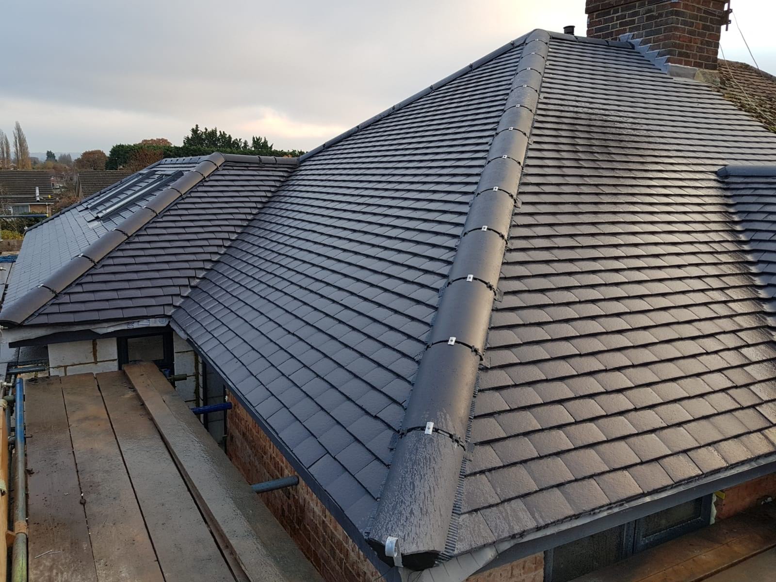 Roofers re-tiling a pitched roof on a South Wales home